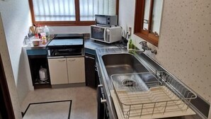 Een kleine keuken met een magnetron, spoelbak en een klein raam.