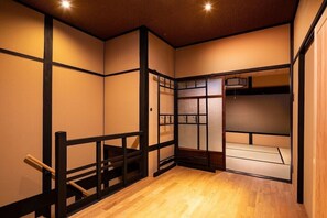 A traditional Japanese room with tatami flooring, sliding doors, and a low wooden bench. - Tsumugi Hachijo Minamotocho (Kyoto)