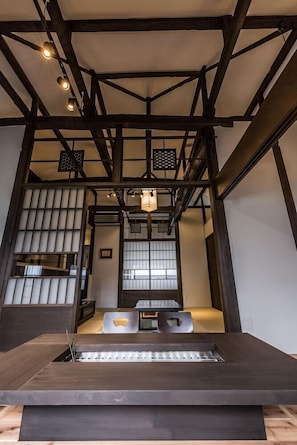 Ein modernes Interieur mit einem zentralen Tisch, Holzbalken und einer traditionellen Schiebetür.
