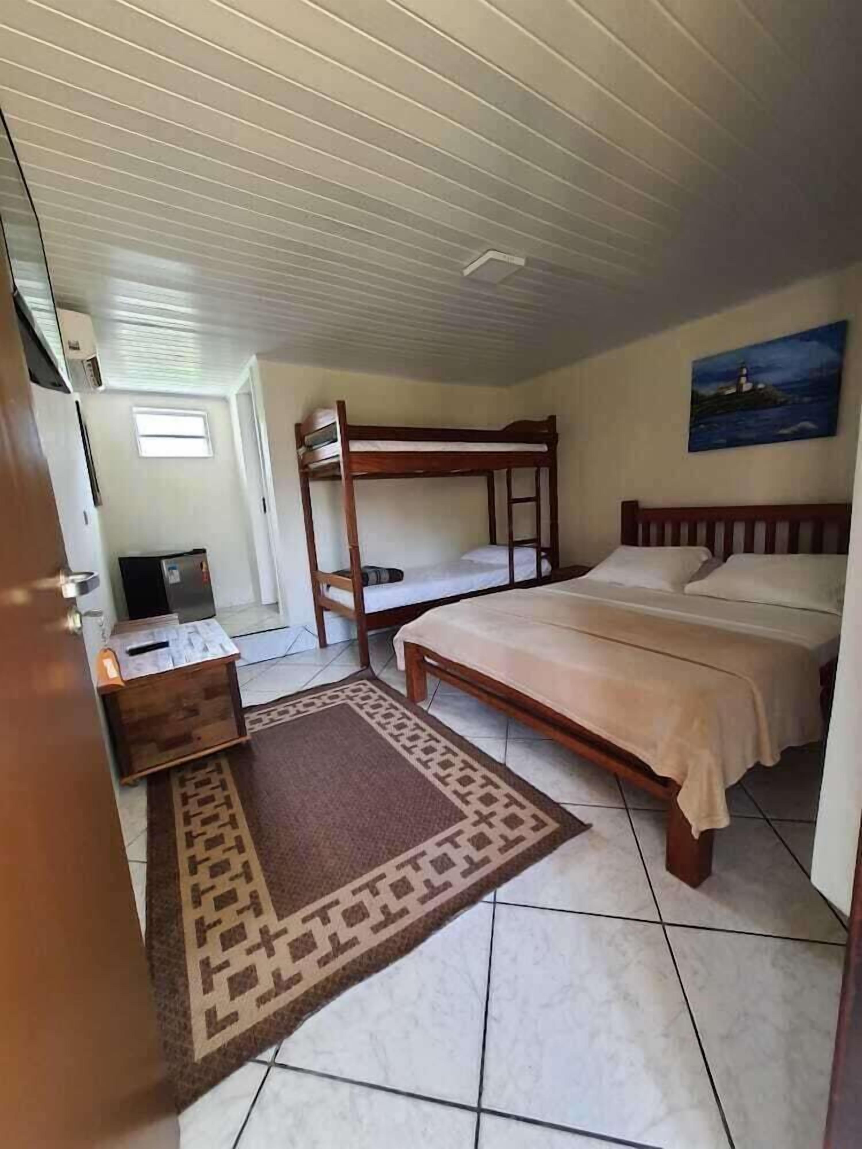 A room with a bunk bed, a desk with a chair, a television, and a painting on the wall.