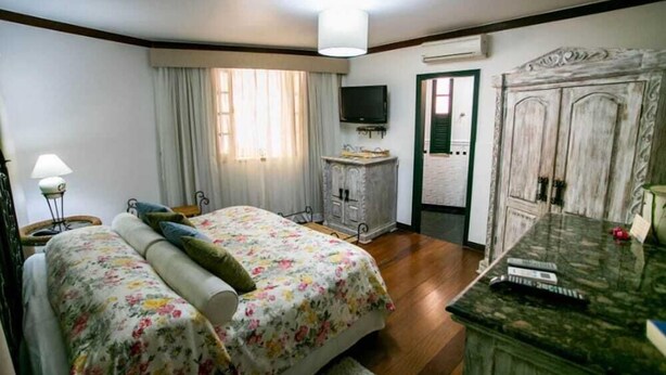 A bedroom with a bed, a dresser, a television, and a door leading to another room. - Bomtempo Ii Chales Da Mata Ex Villaggio Imperiale Itaipava (Petrópolis)