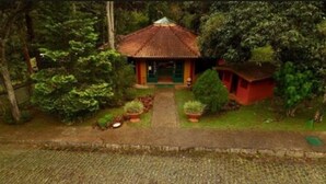 A small, single-story building with a tiled roof, surrounded by lush greenery and a well-maintained garden. - Bomtempo Ii Chales Da Mata Ex Villaggio Imperiale Itaipava (Petrópolis)
