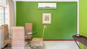 A room with green walls, wicker chairs, a glass table, an air conditioning unit, and a framed picture. - Bomtempo Ii Chales Da Mata Ex Villaggio Imperiale Itaipava (Petrópolis)