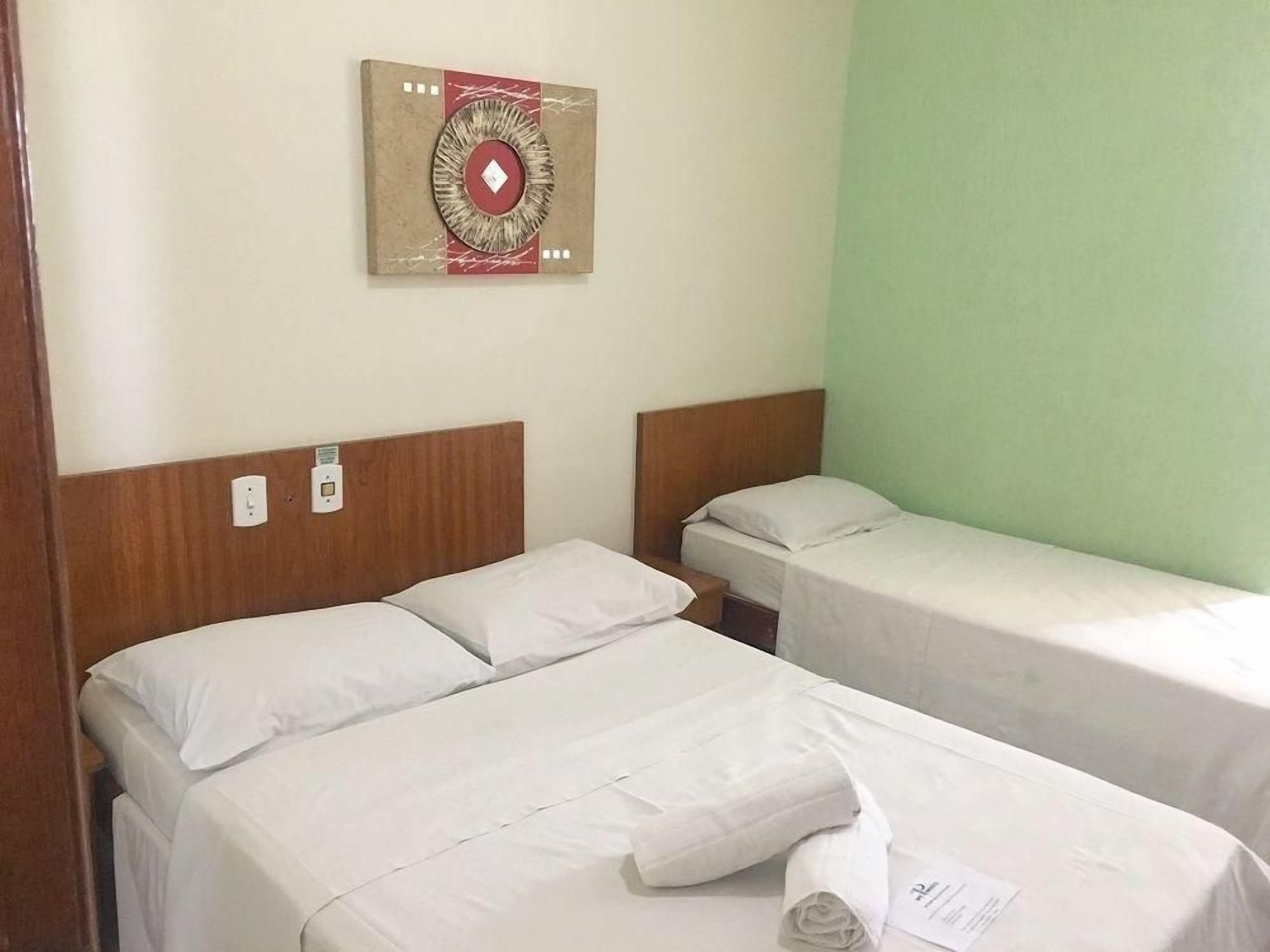 Une chambre d’hôtel avec deux lits, une œuvre d’art accrochée au mur et un mur de couleur verte.