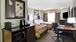 A hotel room with a kitchenette, two beds, a desk, a TV, and artwork on the walls. - Weyburn Canalta Hotel (Weyburn)