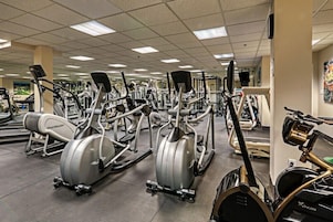 Uma academia com diversos equipamentos de exercícios, incluindo esteiras, elípticos e aparelhos de musculação.