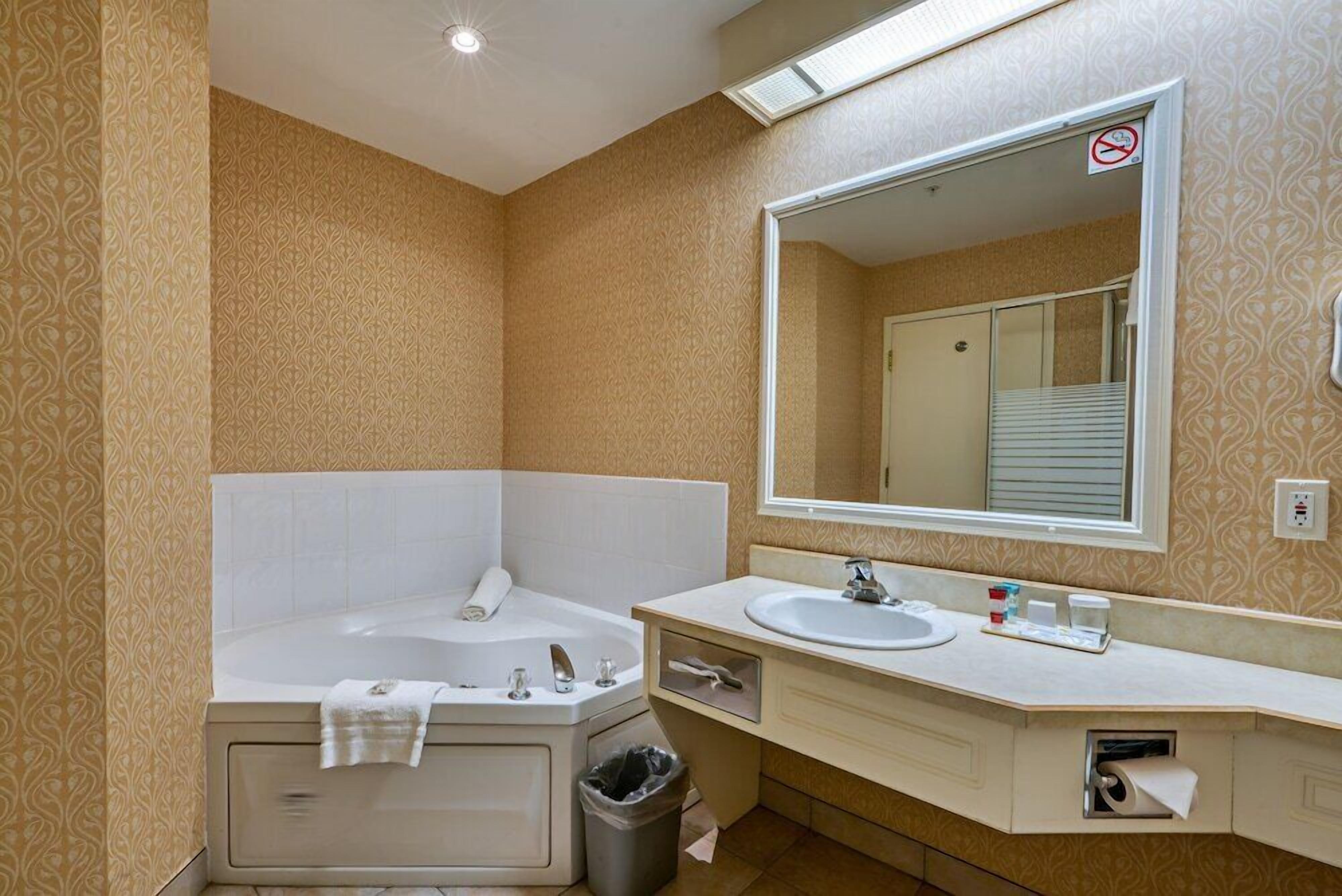 A bathroom with a bathtub, sink, mirror, and towel rack.