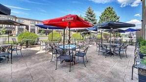 An outdoor patio area with tables and chairs, some under red and blue umbrellas, and a fountain in the center. - Casablanca Winery Inn (Grimsby)