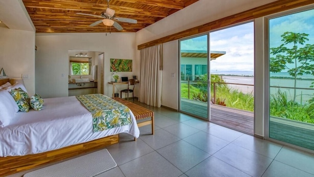 A bedroom with a wooden ceiling, a bed, a desk, and a view of the ocean. - El Castillo - Adults Only (Ciudad Cortés)