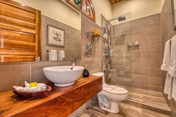 A modern bathroom with a wooden vanity, a large white sink, a toilet, and a glass shower enclosure. - El Castillo - Adults Only (Ciudad Cortés)