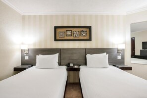 A hotel room with two beds, a headboard, a framed artwork above the beds, and a nightstand with a phone and lamp. - Copantl Convention Center (San Pedro Sula)