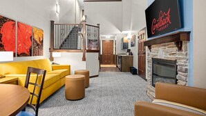 Eine moderne Hotelhalle mit einem gelben Sofa, einem Kamin und einer Treppe zum Obergeschoss.