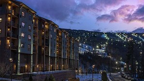 Ein mehrstöckiges Hotel mit Balkonen, vor einer verschneiten Landschaft und einer Bergkulisse.
