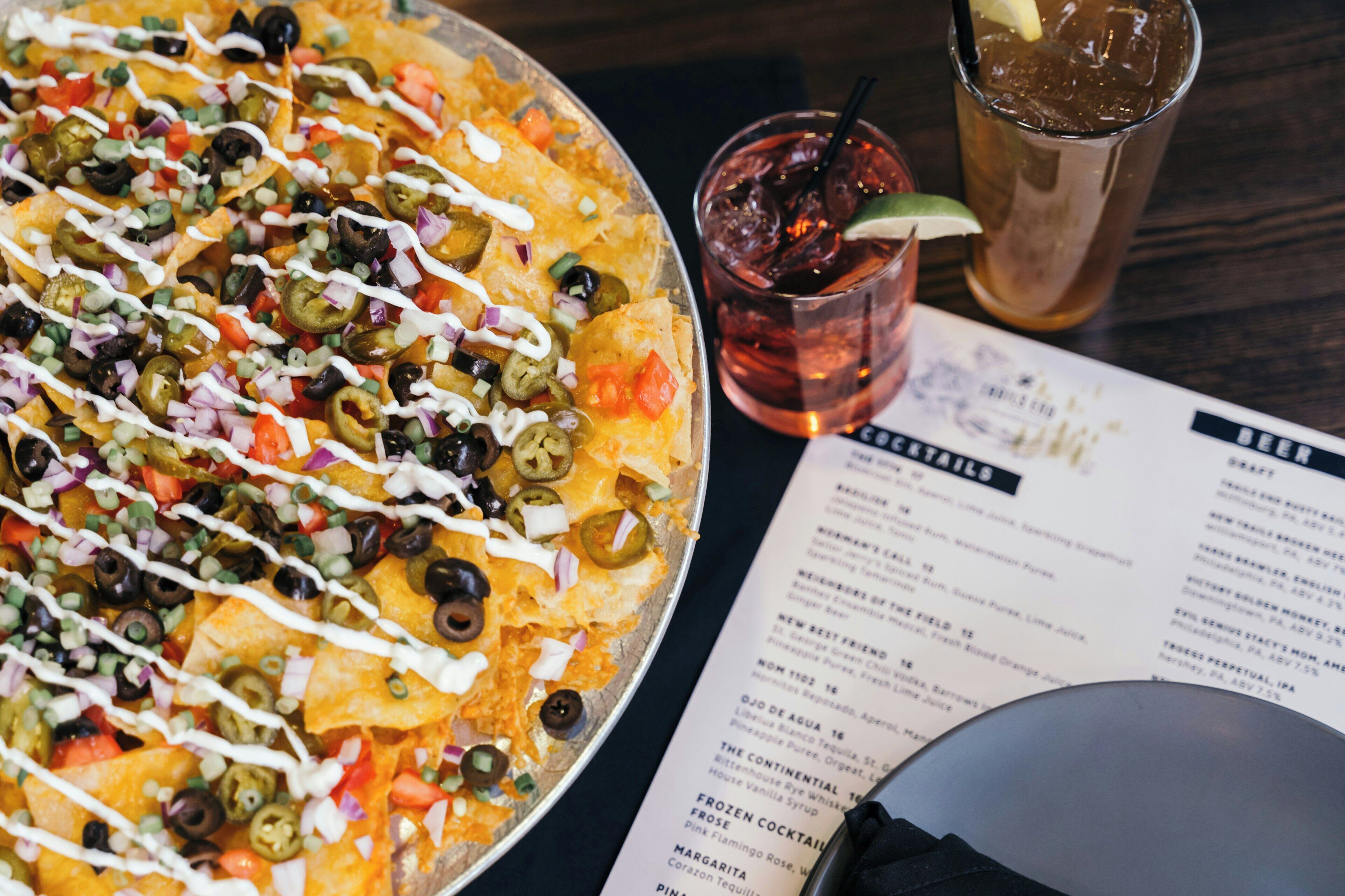 Nachos med olika tillbehör och en meny på bordet.