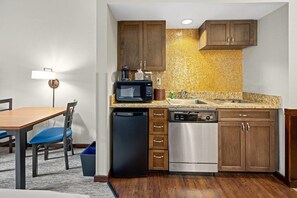 A compact kitchen with wooden cabinets, a microwave, a dishwasher, and a sink. - Camelback Lodge & Aquatopia Indoor Waterpark (Tannersville)