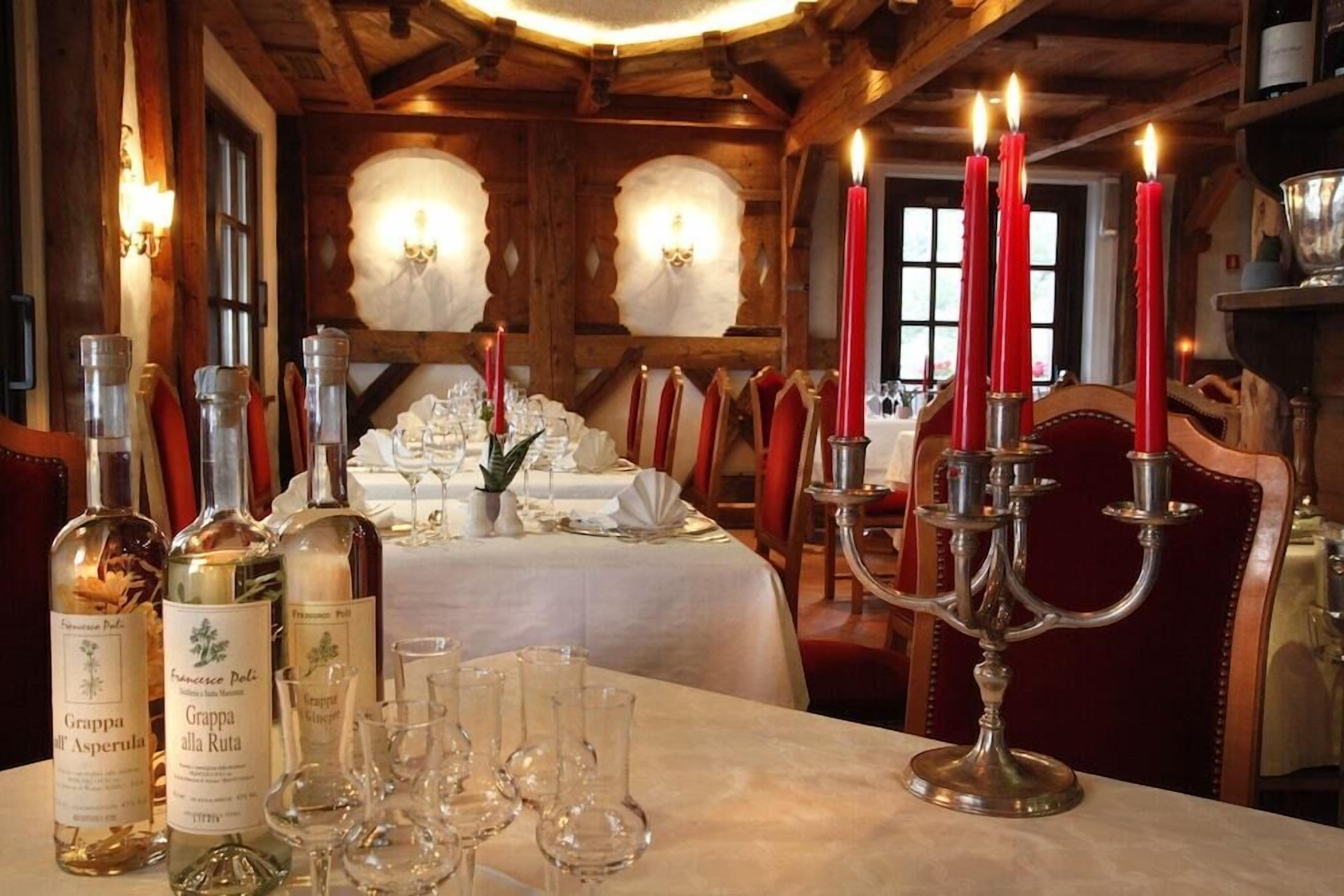 Un tavolo da pranzo apparecchiato con bottiglie di vino, bicchieri e un candelabro con candele.