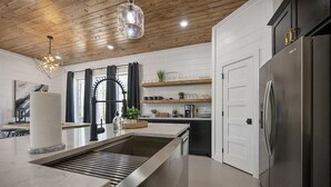 Una cocina moderna con una isla central, electrodomésticos de acero inoxidable y techo de madera.