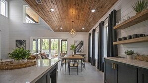 Una cocina moderna con techo de madera, una isla central y armarios oscuros.