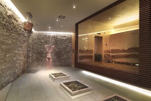 Una habitació d'spa amb parets de pedra, un mirall gran i una banyera d'hidromassatge.