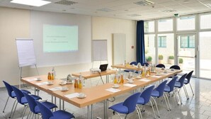 A conference room with a long table, blue chairs, a projector screen, and a whiteboard. - Hotel Restaurant Hoettche (Dormagen)