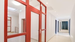 A hallway with a red-framed glass door, a staircase, and a view into another room.