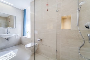 A modern bathroom with a glass shower enclosure, a toilet, and a sink with a mirror. - Hotel Apfelrot (Erding)
