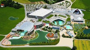 An aerial view of a resort with multiple swimming pools, a large central building, and landscaped areas.