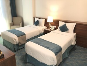Une chambre d’hôtel avec deux lits, chacun étant équipé d’un oreiller et d’une table de chevet avec une lampe et un téléphone.