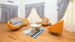A modern living room with a sofa, two armchairs, a coffee table, and a rug. - Tamarind Guesthouse and Suites (Accra)