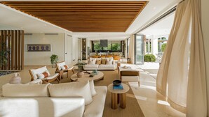 A spacious living room with a modern design, featuring a large sofa, a coffee table, and a dining area.