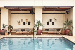 Zona de piscina con mobiliario, plantas en macetas y una piscina.