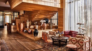 A spacious room with a wooden staircase, a red leather sofa, and various decorative items.