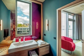 A modern bathroom with a large window, a sink, and a red chair. - Koncept Hotel Josefine (Cologne)