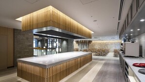 A modern kitchen with a central island, wooden accents, and a stone backsplash. - Okinawa Hinode Resort And Hot Spring Hotel (Naha)