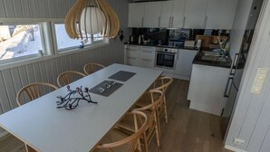 Una cocina moderna con armarios blancos, una isla central y una lámpara colgante.