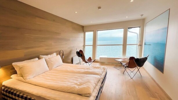 Un dormitorio moderno con una cama grande, vistas al mar y un diseño minimalista.