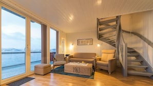 Una sala de estar moderna con piso de madera, un sofá, una silla, una mesa de centro y una escalera.
