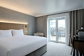 A hotel room with a large bed, a desk, a chair, and a view of the outdoors through a sliding door. - The Quays Hotel Sheffield (Sheffield)