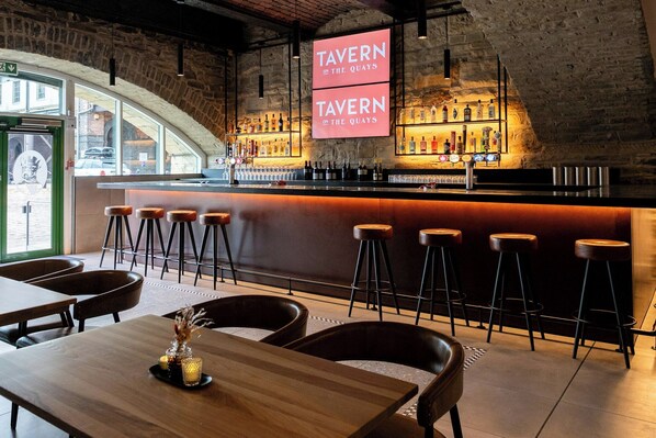 A bar area with stools, a counter with bottles, and a sign that reads 'TAVERN ON THE QUAYS'. - The Quays Hotel Sheffield (Sheffield)