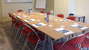 A conference room with a long table, red chairs, water bottles, and papers. - Hotel Restaurant de la Marine (Saint-Herblain)