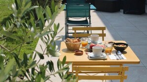 An outdoor breakfast setup with a table, chairs, and various breakfast items. - Hotel Restaurant de la Marine (Saint-Herblain)