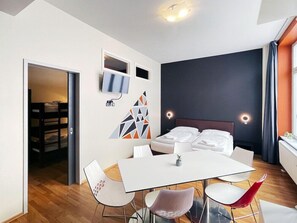 A modern hotel room with a bed, a dining table, and a TV mounted on the wall. - Say Cheese Leipzig Hotel and Hostel (Leipzig)