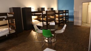 A dormitory room with bunk beds, a dining table with chairs, and a blue accent wall. - Say Cheese Leipzig Hotel and Hostel (Leipzig)