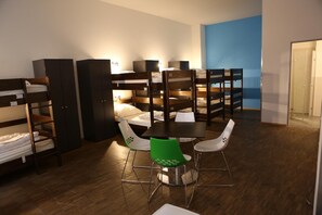 A dormitory room with bunk beds, a dining table with chairs, and a blue accent wall. - Say Cheese Leipzig Hotel and Hostel (Leipzig)