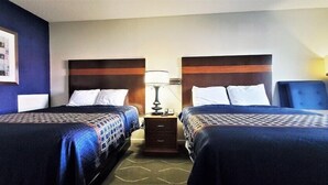 A hotel room with two beds, a nightstand with a lamp, and a framed picture on the wall. - Travelodge Newport News (Newport News)