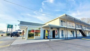 A motel with a single-story structure, a covered front area, and a visible staircase leading to the upper level. - Travelodge Newport News (Newport News)