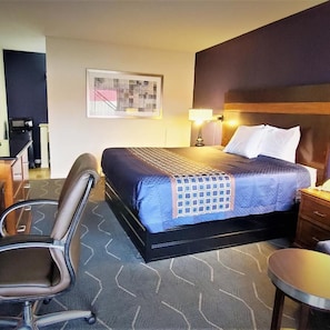 A hotel room with a bed, a desk, a chair, and a small table. - Travelodge Newport News (Newport News)