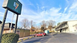 A parking lot with a red car, a building with a sign reading "ECONOMY INN", and a clear blue sky. - Travelodge Newport News (Newport News)