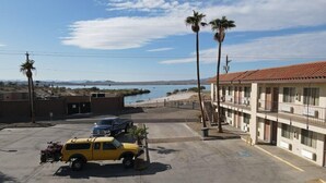 A motel with a parking lot, a beach view, and palm trees. - Swai Hotel (Lake Havasu City)
