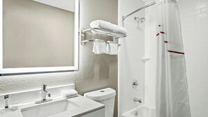 A bathroom with a sink, toilet, and shower area. - Regency Inn & Suites DFW (Euless)